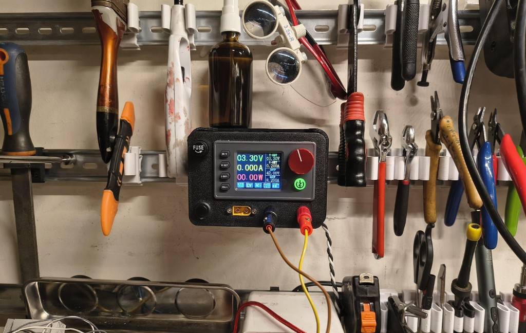 Portable power supply mounted on a DIN rail among workshop tools